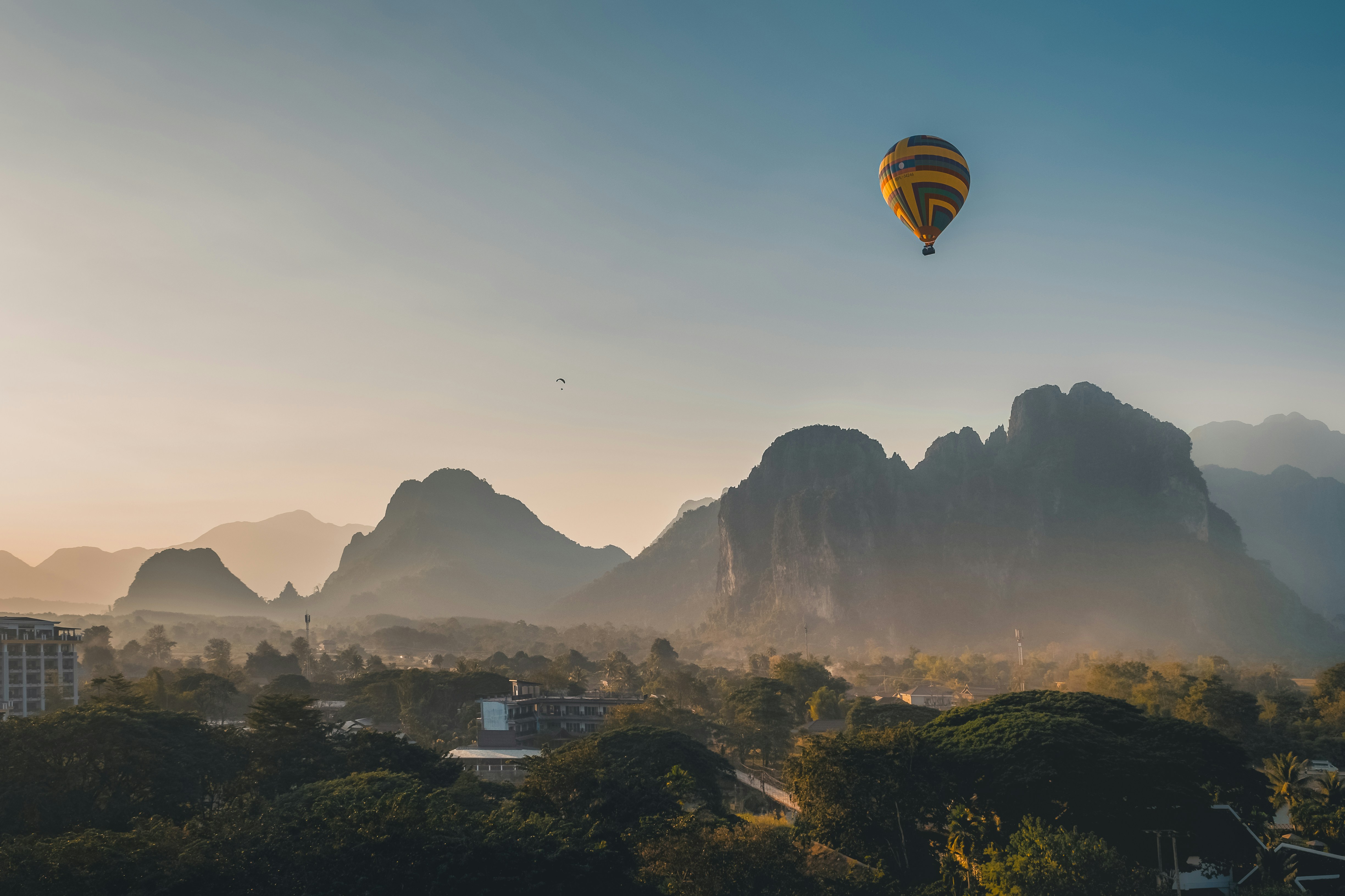 Hot air balloon drifting over karst mountains at sunrise in Vang Vieng, Laos