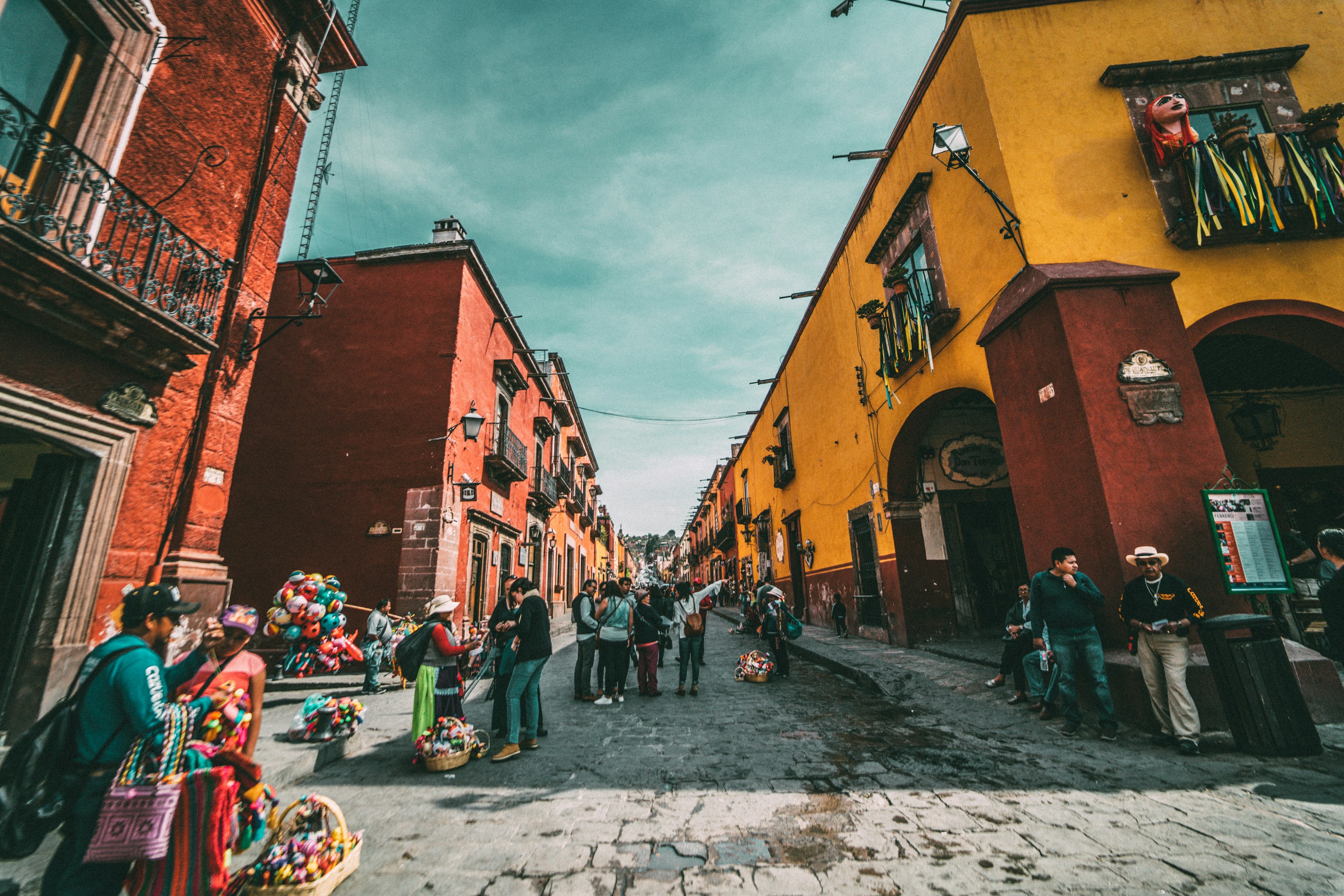 Cobblestone street with orange and yellow colonial buildings and street vendors in San Miguel de Allende, Mexico