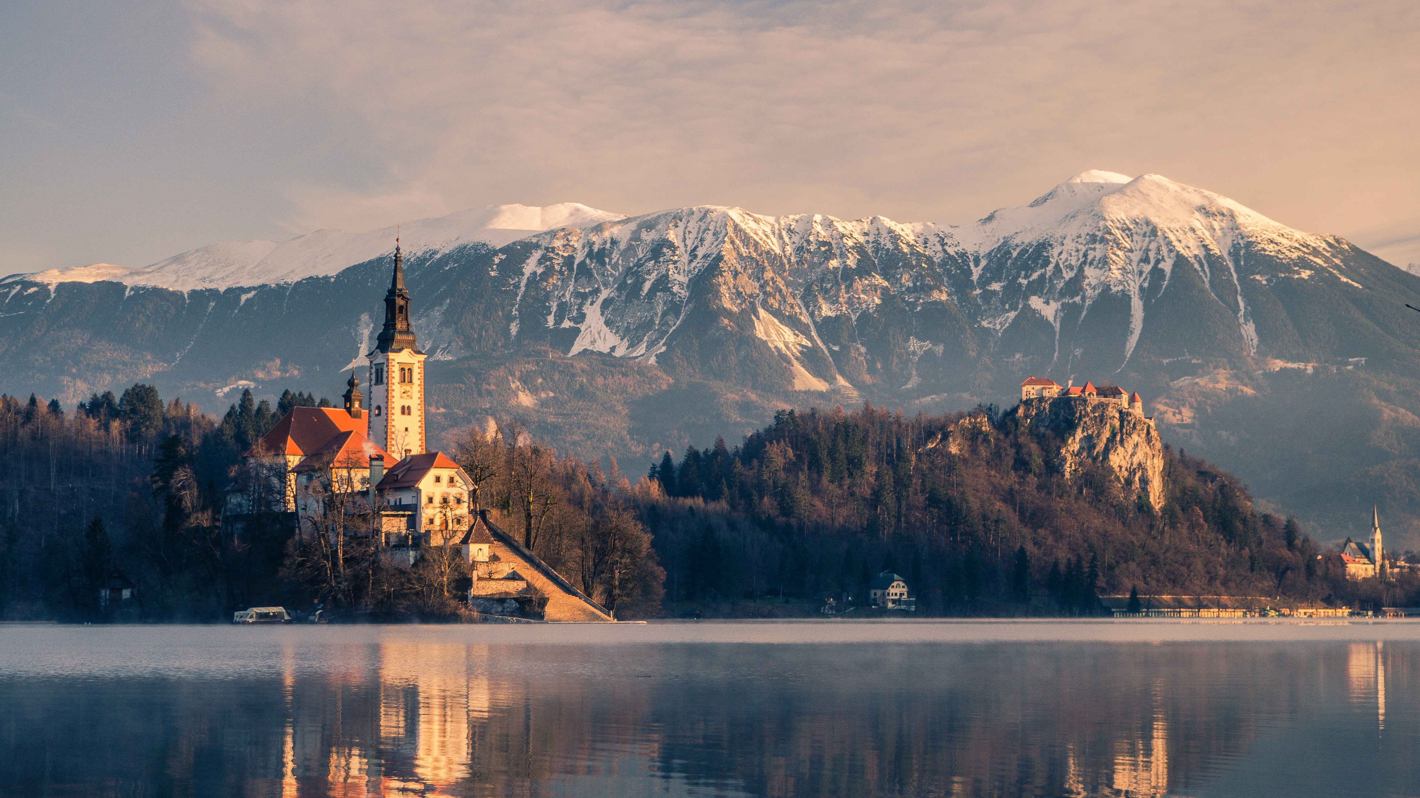 The iconic island church of Lake Bled with snow-capped Julian Alps reflecting in the lake